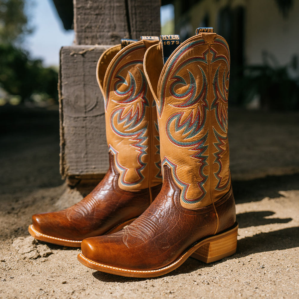Brown and tan cowboy boots with intricate multicolored stitching patterns on the shaft