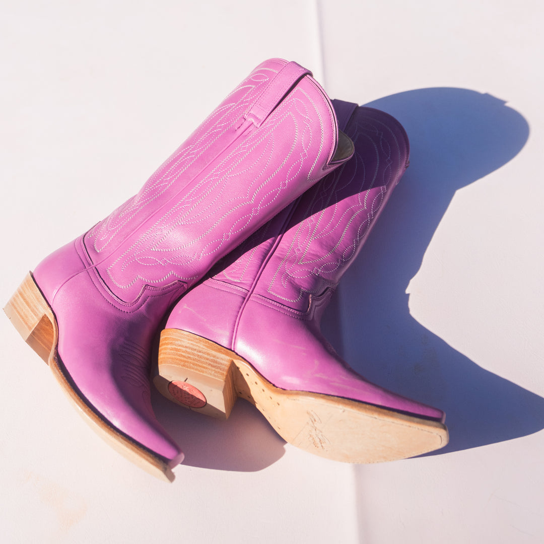 Pair of pink cowboy boots with leather soles on a white background