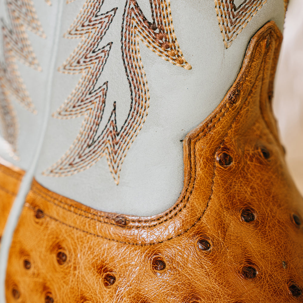 Close up shot of cowgirl boot where the vamp meets the shaft, showing the details and texture of the ostrich material on the vamp and the turquoise upper featuring brown and tan detailed stitching