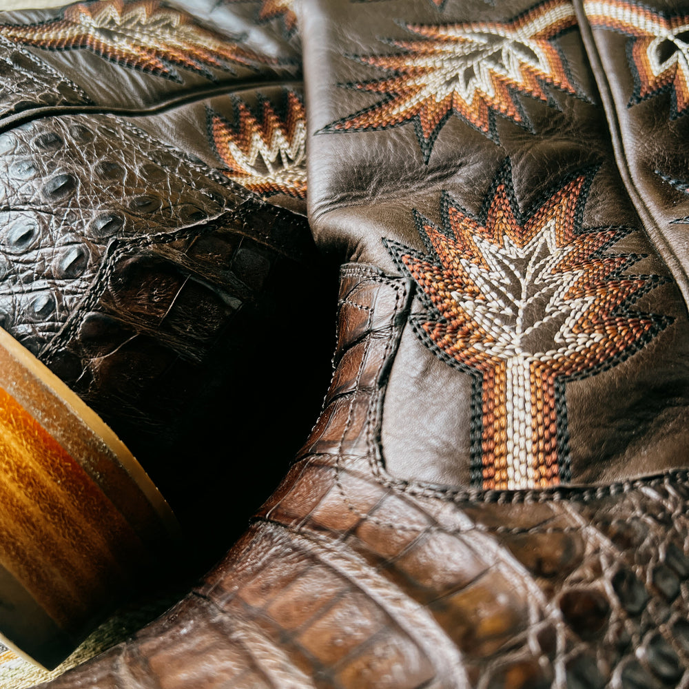 Detail shot of brown caiman cowboy boot showing orange and white intricate stitching details