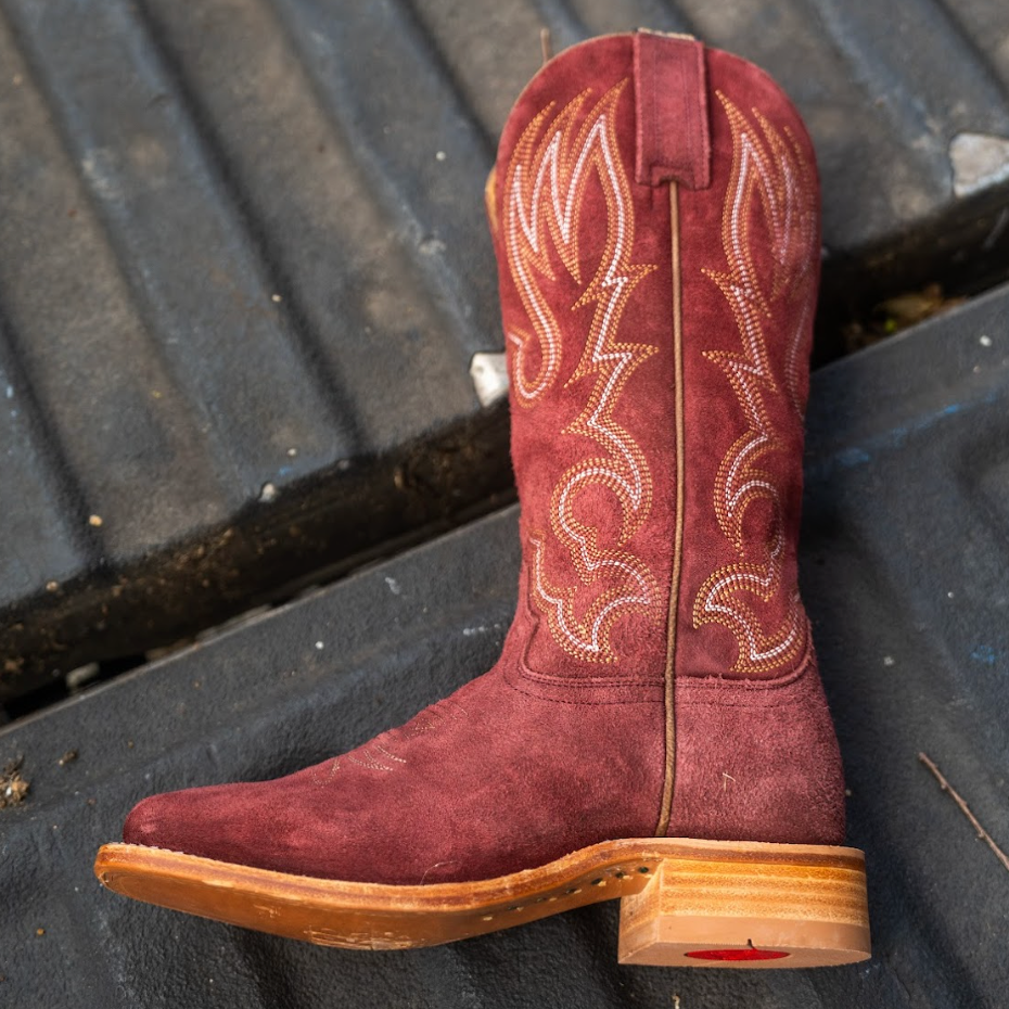 Red cowboy boot with white stitching on a dark textured surface